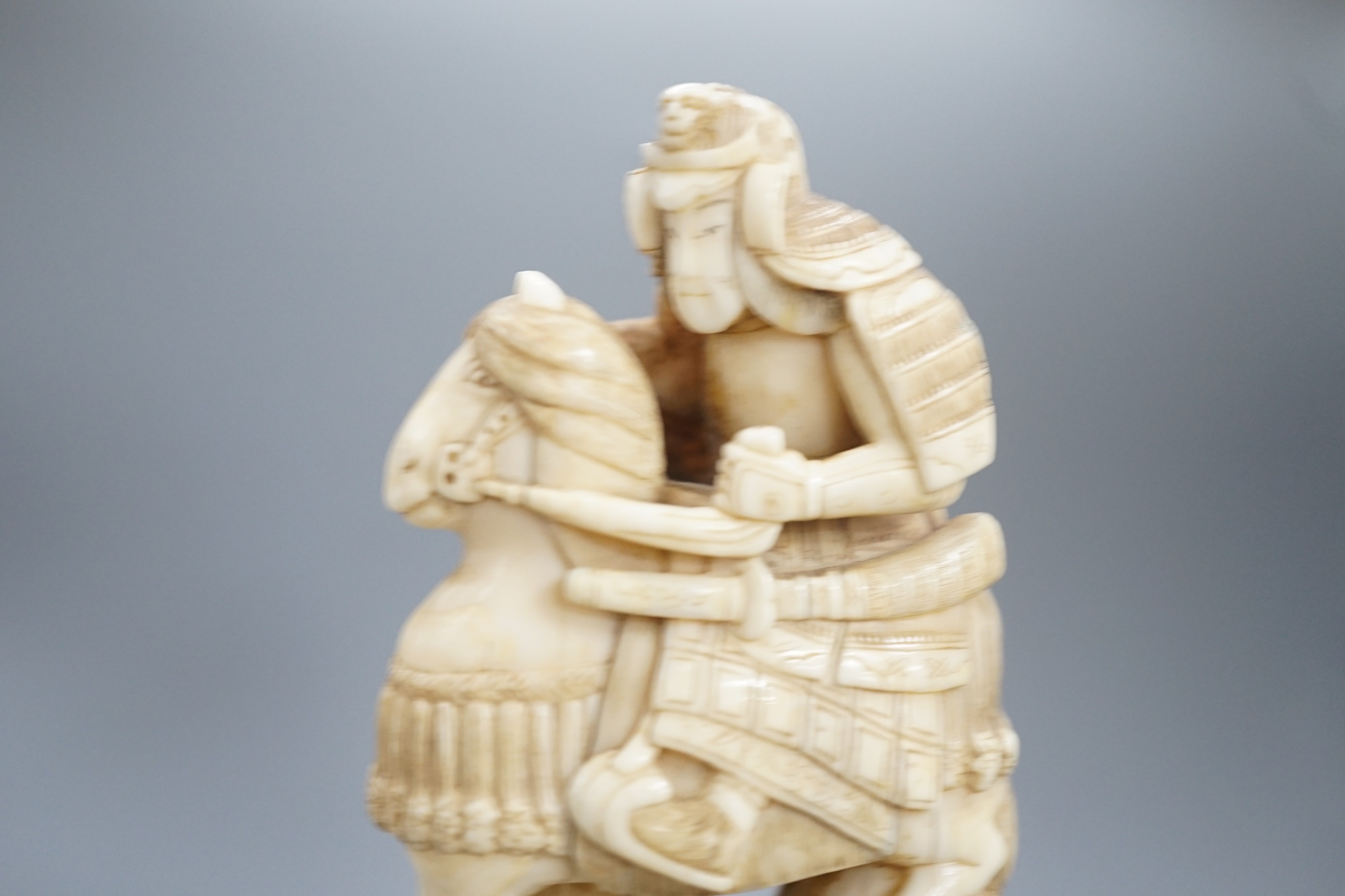 A Japanese ivory okimono of a samurai on horseback, with an attendant behind him, signed, late 19th century 12cm